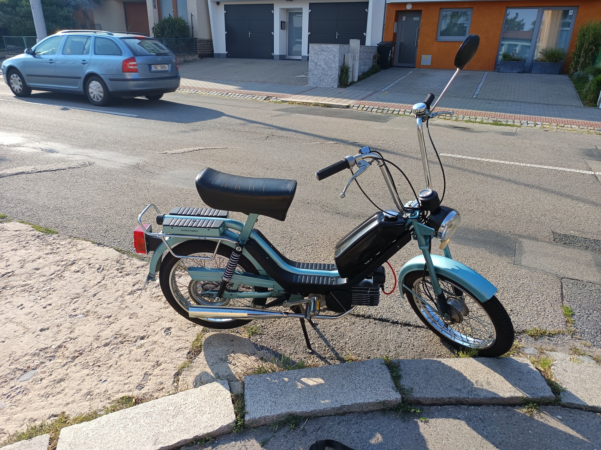 An 80's moped standing on a sidewalk.